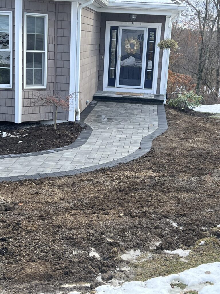 Walkway that ramps to the front door steps in Cambridge Ledgestone 3 piece kit shown in the color Natural Onyx with a Coal border.