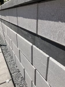 Retaining wall built using Cambridge Omega wall blocks shown with a Coal Platinum Smooth strip.