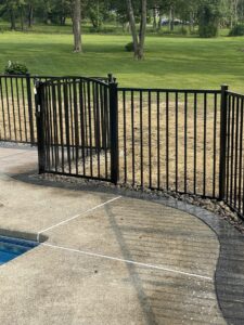 Pool fencing constructed of aluminum with an arched gate and ball caps.