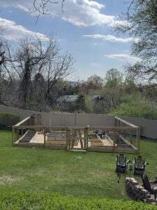 Wooden Garden Enclosure in front of vinyl privacy fence in the color Adobe.