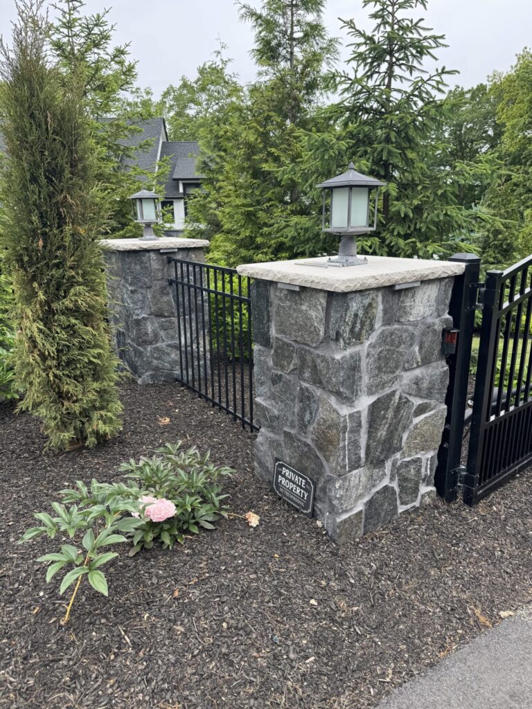Pillars are made of R-Stone Mosaic veneer in the color Nantucket Blue capped with a Limestone topper. These are accompanied by aluminum fencing and gates that are controlled by American Armor Automation.