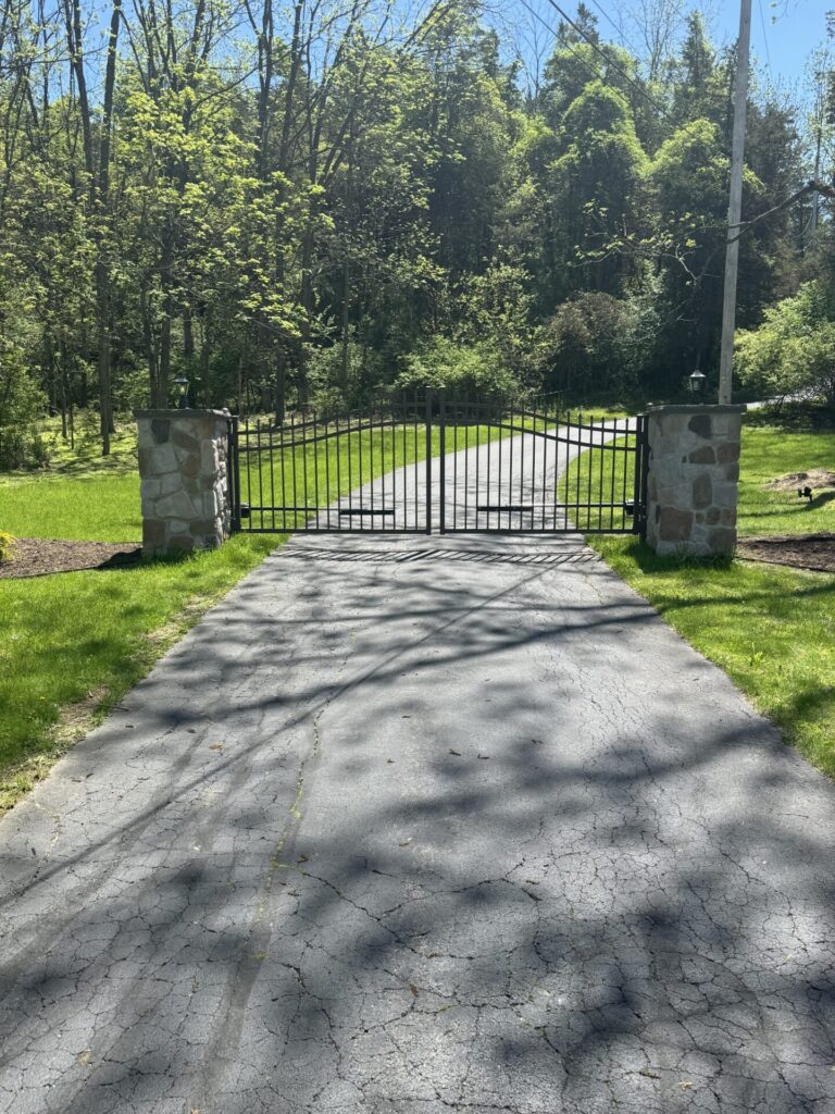 R-Stone driveway pillars shown in Mosaic Country Fieldstone accompanied by an aluminum gate controlled by American Armor Automation.