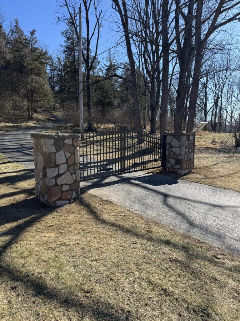 R-Stone driveway pillars shown in Mosaic Country Fieldstone accompanied by an aluminum gate controlled by American Armor Automation.