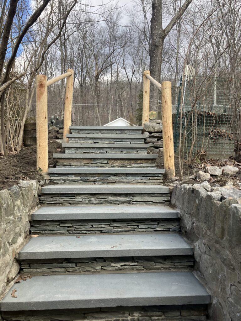 Rebuilt staircase using natural bluestone stair treads and natural stacked bluestone risers accompanied by a custom round cedar railing.