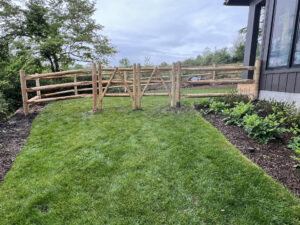 Round cedar three-rail fence with black welded wire mesh.