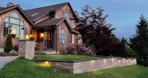 Retaining wall and pillars constructed from Versa-Lok Hickory Square Foot Blocks with black bluestone caps. Brass under lighting by Volt was used to enhance the walls appearance at night.