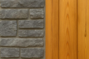 Close-up of cool gray stone veneer paired with vertical cedar wood siding, showcasing a stylish blend of textures and tones for a modern natural exterior.