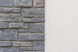 Close-up of medium-toned cool gray stone veneer next to smooth white stucco, showing a clean and cohesive modern exterior material combination.