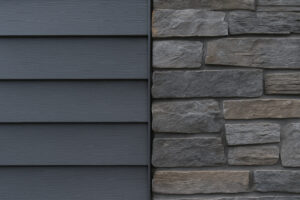 Close-up of dark gray vinyl siding paired with cool-toned stacked stone veneer, showcasing a modern exterior finish with complementary textures and deep hues.