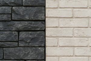 Close-up of dark cool-toned stone veneer next to whitewashed brick siding, showcasing a bold and balanced exterior material pairing with contrasting textures.